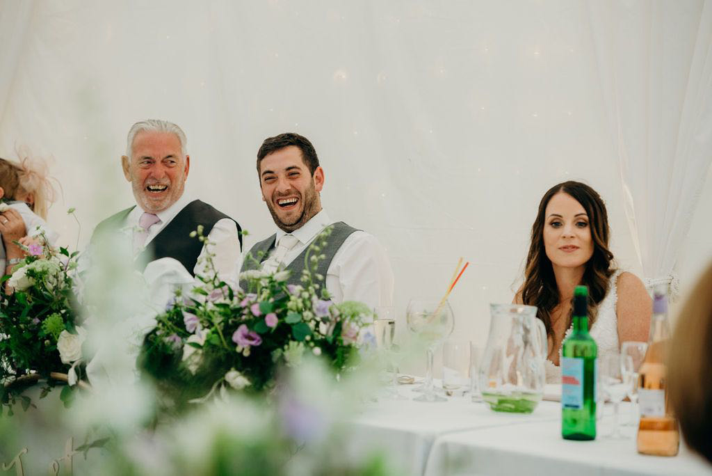 Groom and father laughing during wedding speeches