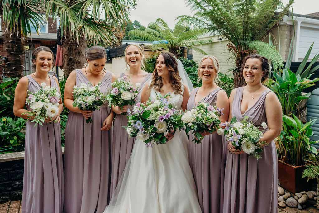 Bride with her bridesmaids all holding pink and white bouquets