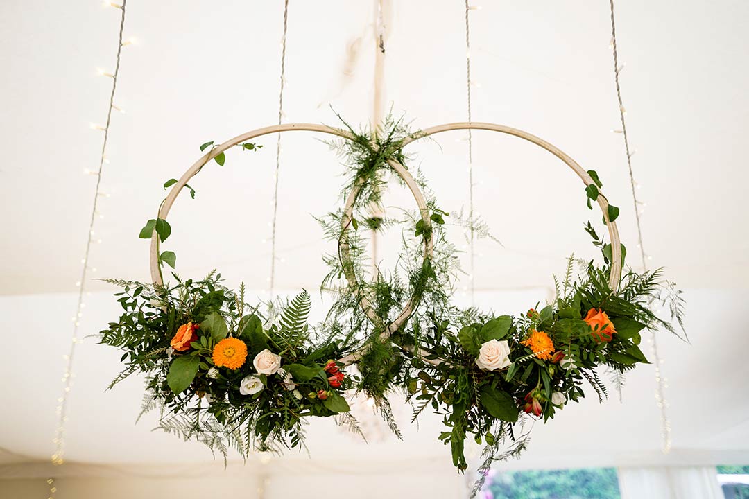 Hoops decorated with flowers below marquee ceiling